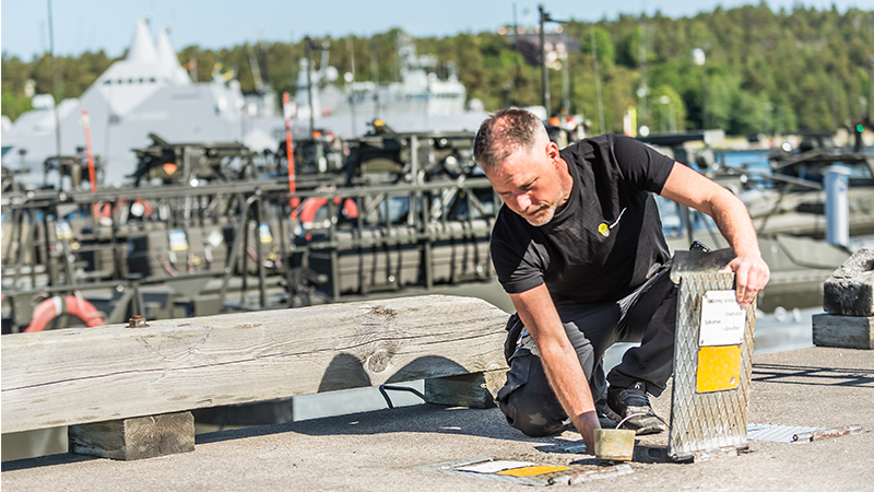 En person öppnar en lucka på en stor brygga där stridsbåtar ligger förtöjda