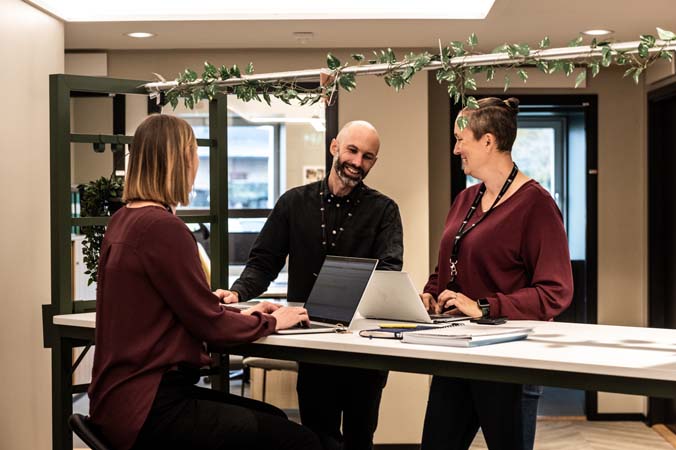 3 personer jobbar vid ett ståbord
