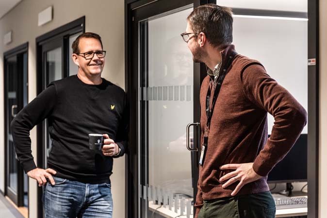 Två personer står i en kontorskorridor och pratar