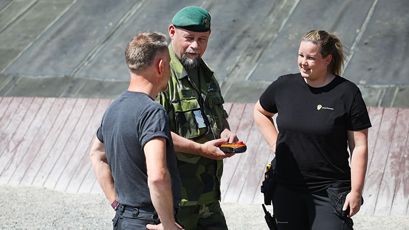 Två medarbetare pratar med en person från Försvarsmakten på en skjutbana. Foto: Peter Malmrup