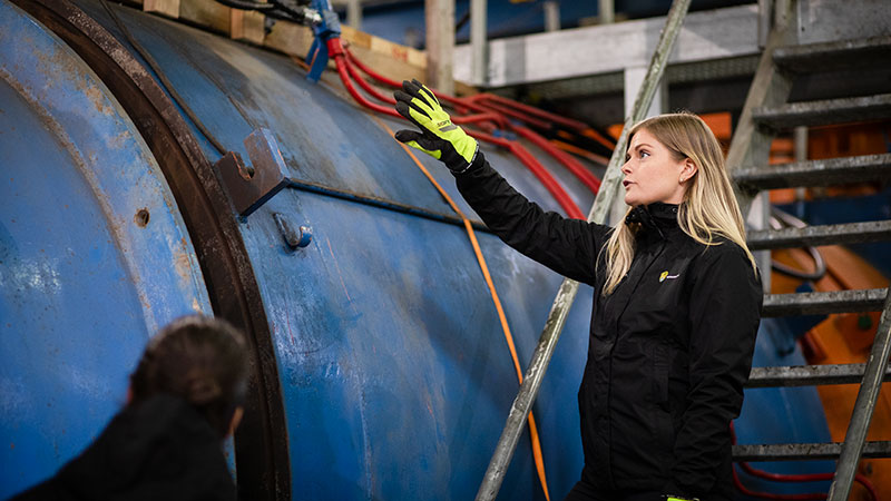 En person står i en verkstad och pekar uppåt.