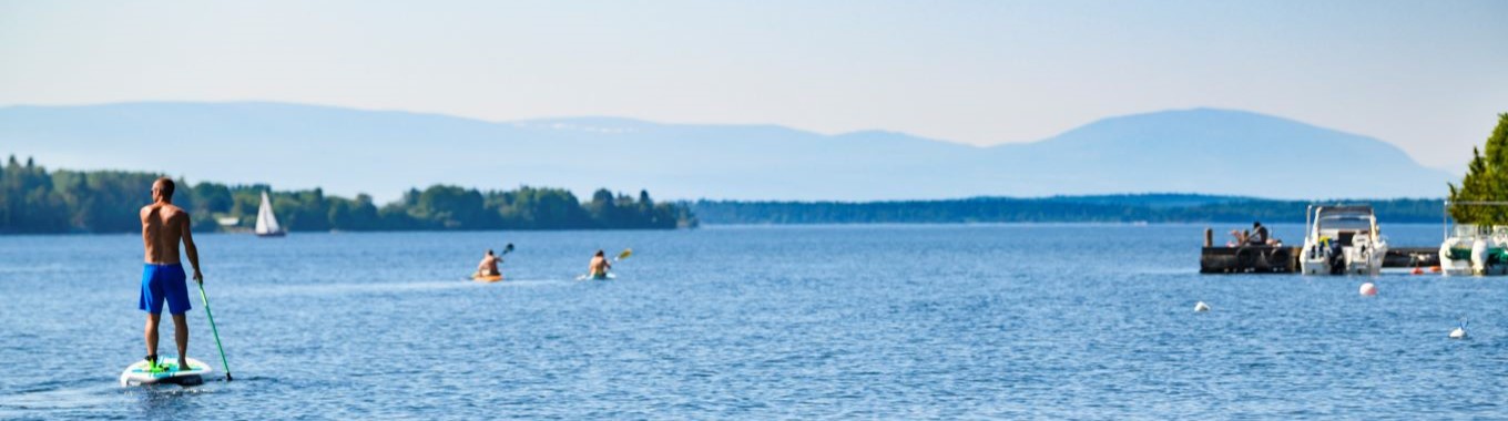En man paddlar stående på en supbräda på Storsjön.
