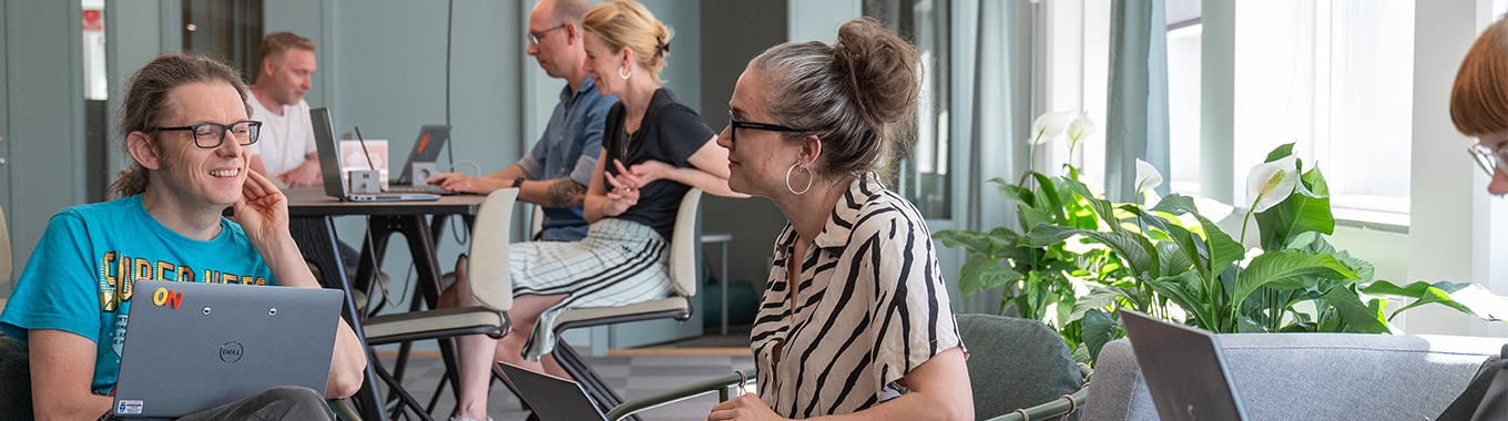 En kvinna och en man sitter och samtalar i ett öppet kontorslandskap.